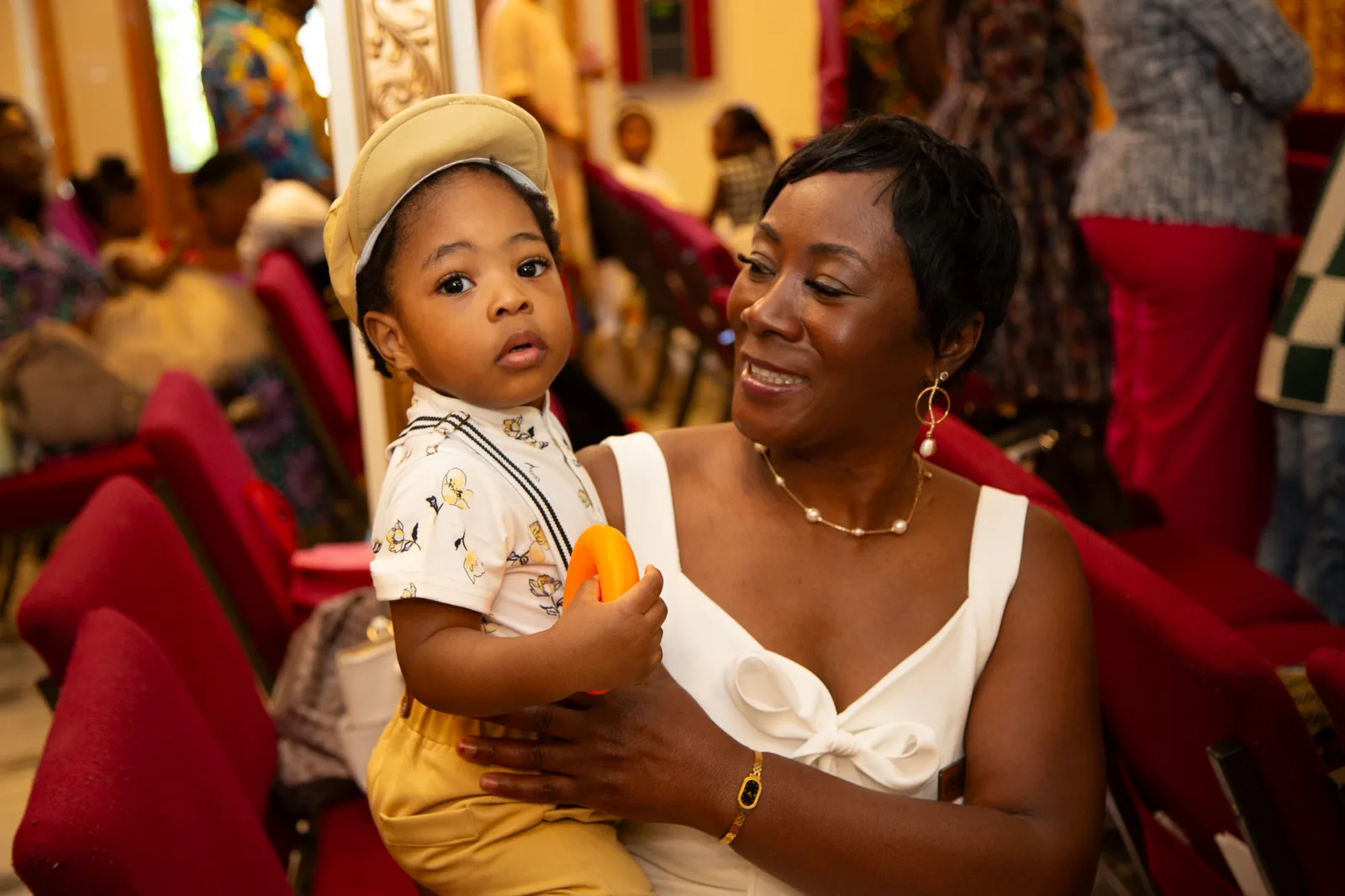 A young mother beams as her toddler looks at the camera — family at church