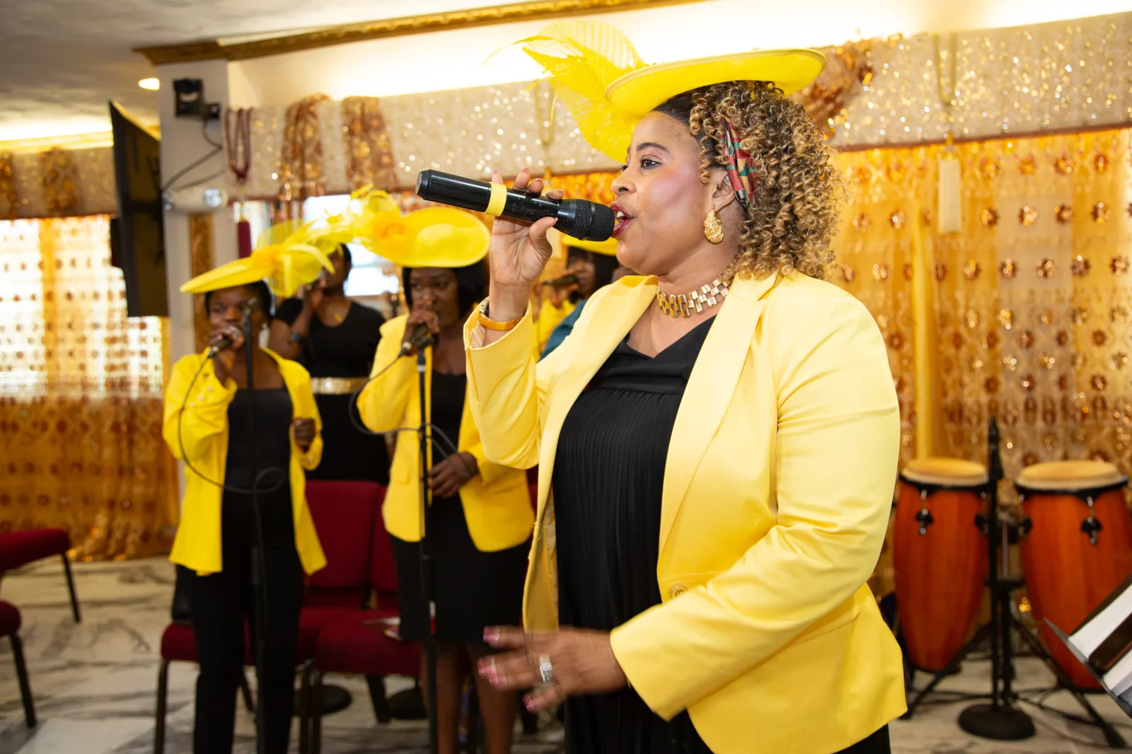 Choir lead vocalist in full yellow regalia — guitarist visible behind